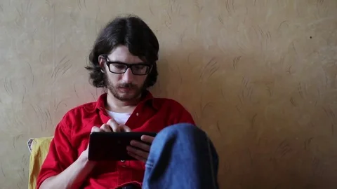 A young man with a gadget lying on sofa in his room 動画素材 82211103