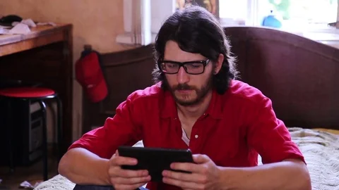 A young man with a gadget lying on sofa in his room 動画素材 82211366