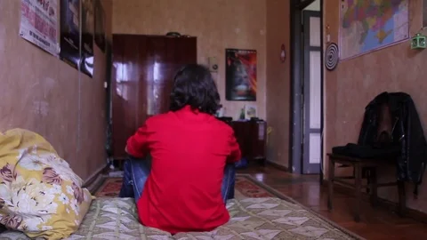 A young man with a gadget lying on sofa in his room 動画素材 82211566