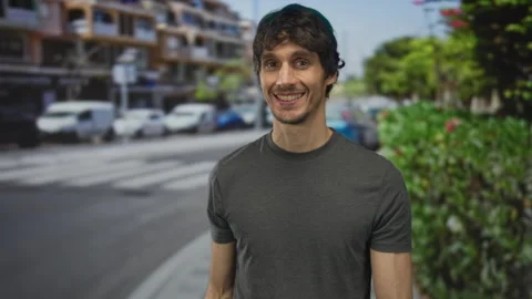 Young man gestures with open palm towards empty sidewalk on sunny city stre.. Stock Footage 315628355
