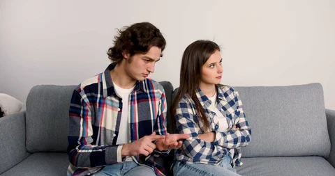 Young man gesturing while talking to offended girlfriend in living room Stock Footage 123966572