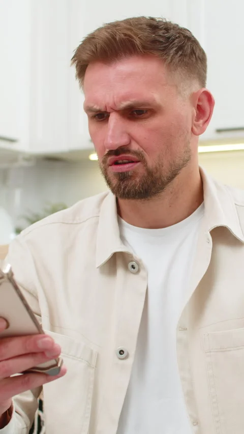 Young man gets alarming smartphone alert frowns asks why it happened anxious Stock Footage 347054895