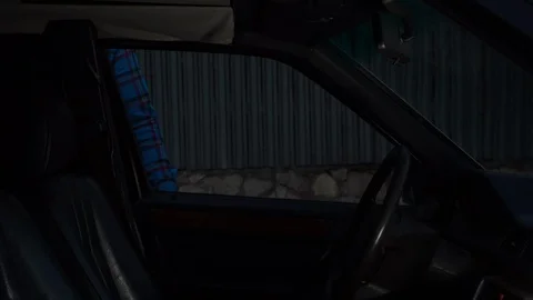 A young man gets into a car and starts to drive a car. Side view. 库存影片 128208696