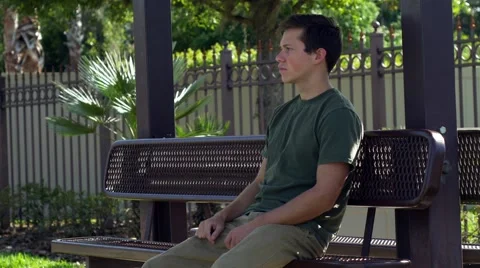 Young man gets frustrated sitting at bus stop, 4K Stock Footage 48703067