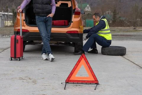Young man gets a help with spare wheel replacement. Punched wheel on the road Foto stock