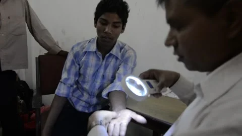 A young man gets his hand checked for leprosy in pop up clinic in southern Nepal Stock Footage 252368075