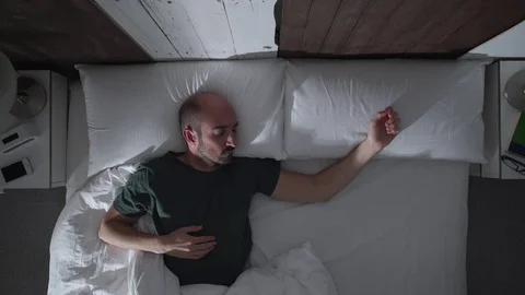 Young man is getting cold in bed at night Stock Footage 71372008