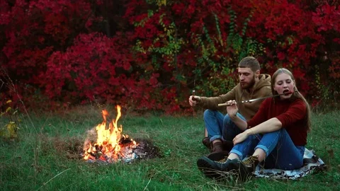 Young man getting up coming towards camera while blonde girl eats fried sausage Stock Footage 99423654