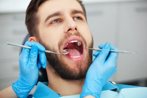 Young man getting his teeth checked by a dentist. Stock Photos