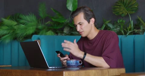 Young man getting message while sitting in a cozy coffee shop with mobile phone Stock Footage 163931661