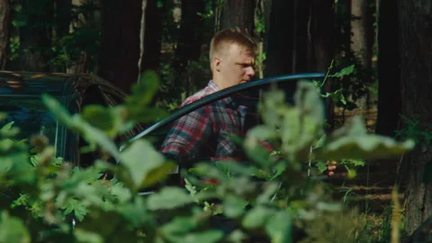 Young Man Getting Out of Car in Forest Rack Focus Shot Stock Footage 245797597
