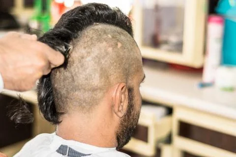 A young man is getting shaved his head at a barber shop Stock Photos