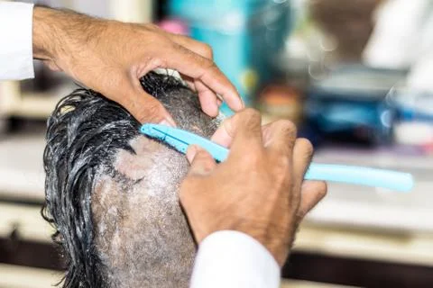 A young man is getting shaved his head at a barber shop Stock Photos