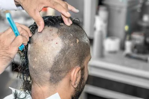 A young man is getting shaved his head at a barber shop Stock Photos