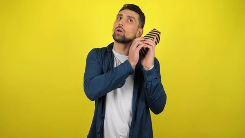 A young man with a gift in his hands, cowards a box near his ear Stock Footage 119862767