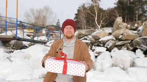 Young man gives a gift on the background of snow and ice 스톡 동영상 101316939