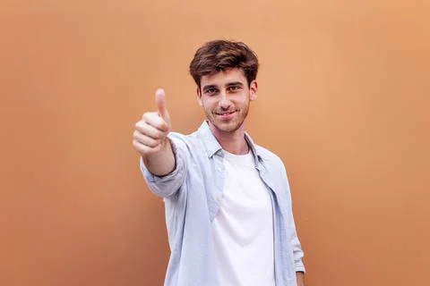Young man giving a thumb up gesture while smiling Stock Photos