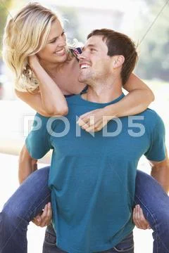 Young man giving woman piggyback outdoors Stock-Fotos