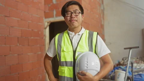 Young man with glasses and high-visibility vest holds helmet at constructio.. 스톡 동영상 289332788