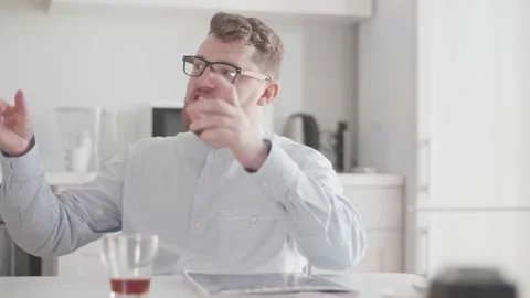 A young man in glasses and stylish light clothes communicates over a homemade Stock Footage 156958295