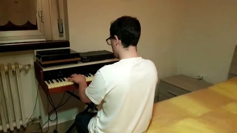 Young man with glasses and white t-shirt composing and playing piano in his.. Stock Footage 243126495