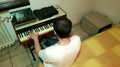 Young man with glasses and white t-shirt composing and playing piano in his.. Stock Footage 243126517