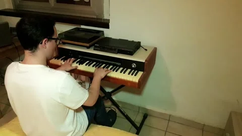 Young man with glasses and white t-shirt composing and playing piano in his.. Stock Footage 243126520