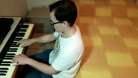 Young man with glasses and white t-shirt composing and playing piano in his.. Stock Footage 243126524