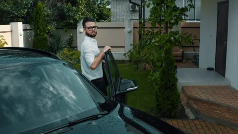 Young man in glasses with a beard gets out of a black car Stock Footage 128743344