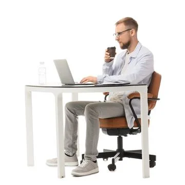 Young man in glasses drinking coffee and working on laptop at a desk, isolate Stock Photos