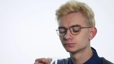 Young man in glasses drinking tea on white background Stock Footage 88659588