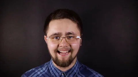 A young man with glasses looks into the camera and laughs. A man with a botod Stock Footage 106350682