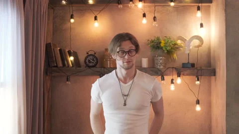 A Young Man With Glasses Looks At The Camera Is In A Cozy Room Stock Footage 137732789