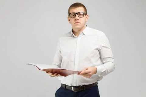 Young man in glasses with an open folder in his hands isolated on a light Stock Photos