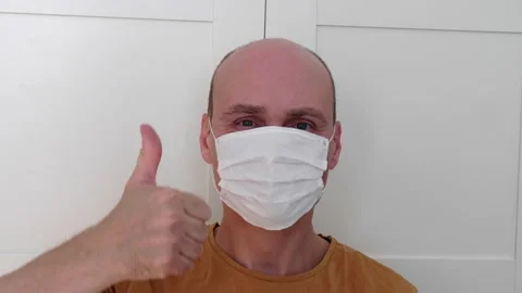 A young man in glasses puts on and takes off protective hygiene mask Stock Footage 152343802