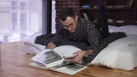 Young man with glasses reading a book Stock Footage 84848569