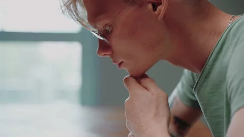Young man in glasses reading a textbook and stressing, with his fist in his chin Video stock 164371979
