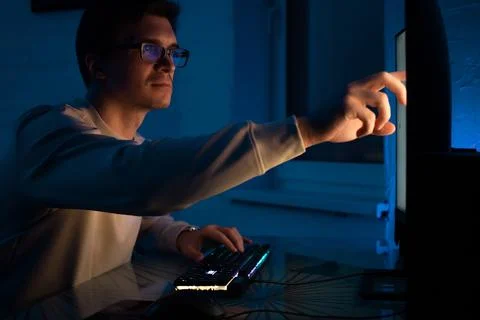 Young man with glasses sits at a computer and is engaged in programming, Stock-Fotos