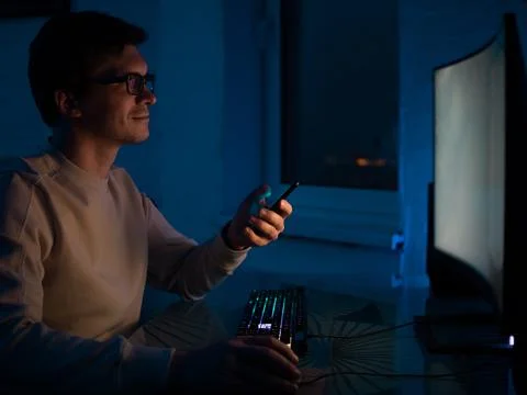 Young man with glasses sits at a computer and is engaged in programming, Stock Photos