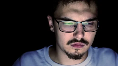 Young man with glasses is sitting at computer at night, tired and sad look Stock Footage 193969482
