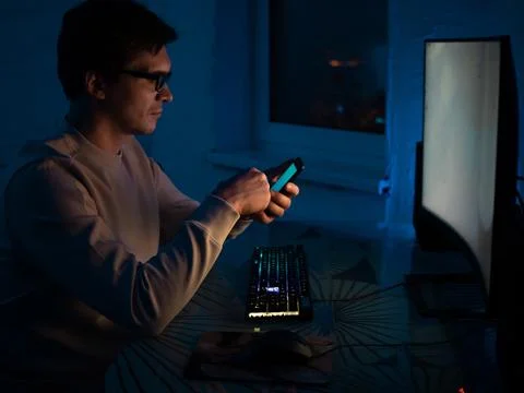 Young man with glasses is sitting at a computer and working on an online project Stock-Fotos
