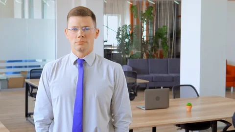 Young man in glasses is smiling in middle of office Stock Footage 111737159