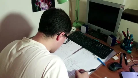 Young man with glasses studying concentrated at his desk with his computer Stock Footage 243126462
