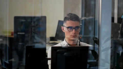Young man in glasses working at a computer at his workplace Stock Footage 144945711