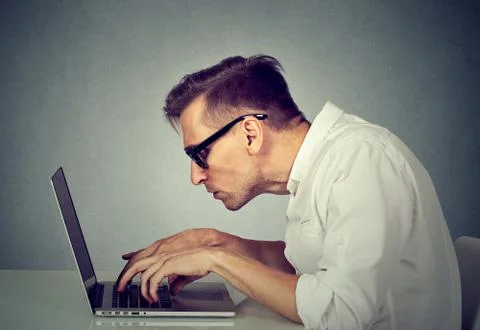 Young man in glasses working on computer sitting at desk Stock Photos