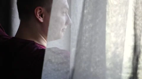 Young man goes next to the window. He is stretching. Video stock 61281103