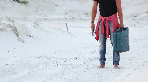 A young man goes through the desert with a canister of gasoline in search of Stock Footage 66415827