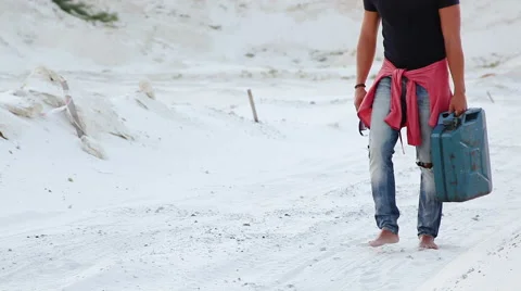 A young man goes through the desert with a canister of gasoline in search of Stock Footage 66415858