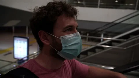 Young man goes up trough escalators on a train station wearing a surgical mas Video stock 133050988