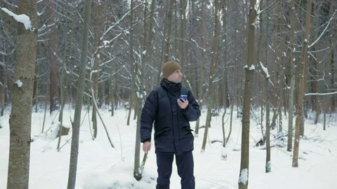 The young man goes in the winter forest and is oriented over the phone. He is Stock Footage 71206426